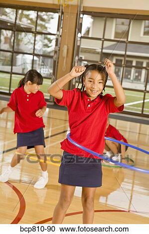 Stock Image - Multi-ethnic girls playing with hula hoops. Fotosearch