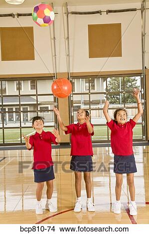 Picture - Multi-ethnic girls throwing sports balls. Fotosearch