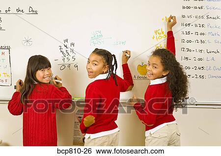 Stock Photograph - Multi-ethnic girls writing on whiteboard. Fotosearch