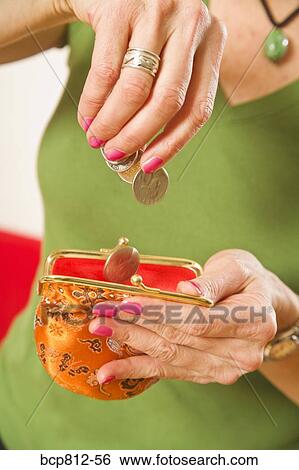 Stock Photograph - Woman dropping coins in purse. Fotosearch