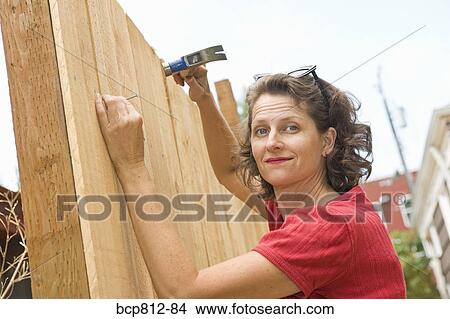 Woman hammering nail into fence View Large Photo Image Picture - Woman hammering nail into fence. Fotosearch