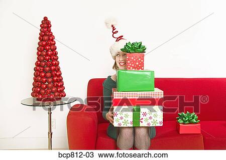 Stock Image - Woman holding stack of Christmas gifts. Fotosearch