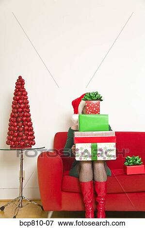 Stock Photo - Woman sitting with stack of Christmas gifts. Fotosearch