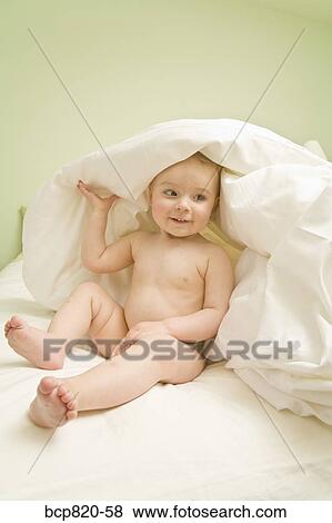 Baby playing under blanket on bed View Large Photo Image Stock Photo - Baby playing under blanket on bed. Fotosearch