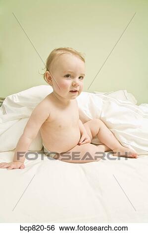 Baby sitting on bed View Large Photo Image Stock Photograph - Baby sitting on bed. Fotosearch