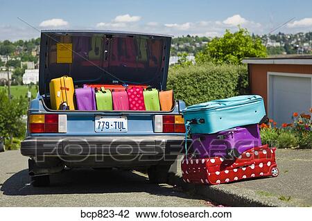 Stock Image - Car trunk loaded with colorful suitcases. Fotosearch