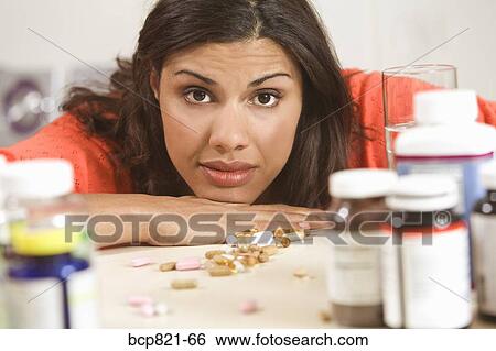 Stock Photograph - Concerned woman looking at vitamins and supplements. Fotosearch