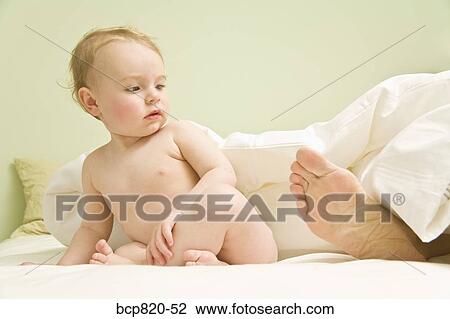 Curious baby looking at mother’s feet in bed View Large Photo Image Stock Image - Curious baby looking at mother’s feet in bed. Fotosearch