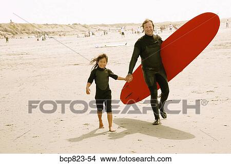 Father and daughter carrying surfboard on beach View Large Photo Image Picture - Father and daughter carrying surfboard on beach. Fotosearch