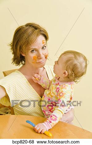 Frustrated mother feeding messy baby View Large Photo Image Stock Photo - Frustrated mother feeding messy baby. Fotosearch