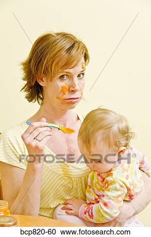 Frustrated mother trying to feed messy baby View Large Photo Image Stock Image - Frustrated mother trying to feed messy baby. Fotosearch
