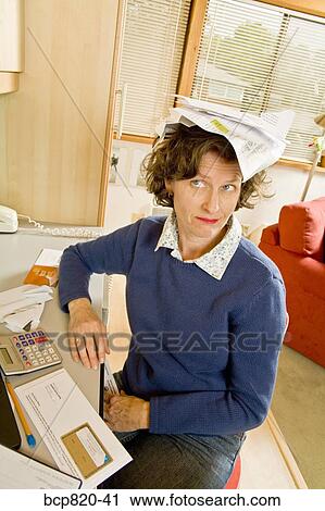 Frustrated woman balancing bills on head in home office View Large Photo Image Stock Image - Frustrated woman balancing bills on head in home office. Fotosearch
