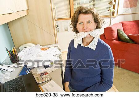 Frustrated woman eating bills in home office View Large Photo Image Stock Photo - Frustrated woman eating bills in home office. Fotosearch