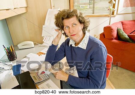 Frustrated woman holding bills in home office View Large Photo Image Stock Image - Frustrated woman holding bills in home office. Fotosearch