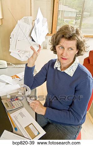 Frustrated woman holding bills in home office View Large Photo Image Stock Photo - Frustrated woman holding bills in home office. Fotosearch