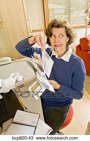 Frustrated woman sorting bills in home office View Large Photo Image Stock Image - Frustrated woman sorting bills in home office. Fotosearch