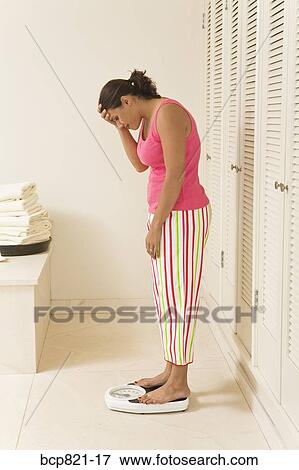 Frustrated woman standing on scale View Large Photo Image Stock Photo - Frustrated woman standing on scale. Fotosearch