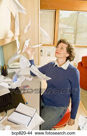 Frustrated woman tossing bills in home office View Large Photo Image Picture - Frustrated woman tossing bills in home office. Fotosearch