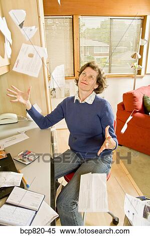 Frustrated woman tossing bills in home office View Large Photo Image Stock Photography - Frustrated woman tossing bills in home office. Fotosearch