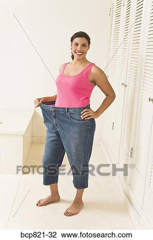 Happy woman in big pants showing off weight loss View Large Photo Image Stock Image - Happy woman in big pants showing off weight loss. Fotosearch