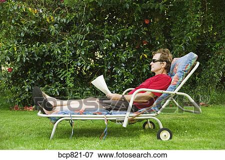 Stock Photo - Man relaxing in lounge chair in backyard. Fotosearch