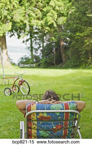 Man relaxing in lounge chair in backyard View Large Photo Image Stock Photography - Man relaxing in lounge chair in backyard. Fotosearch