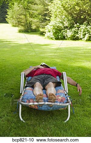 Man with magazine over face relaxing in lounge chair in backyard View Large Photo Image Stock Image - Man with magazine over face relaxing in lounge chair in backyard. Fotosearch