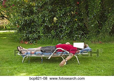Man with magazine over face relaxing in lounge chair in backyard View Large Photo Image Stock Photo - Man with magazine over face relaxing in lounge chair in backyard. Fotosearch