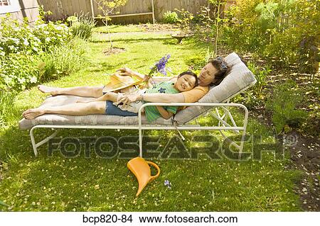 Mother and son sleeping on lounge chair in backyard garden View Large Photo Image Picture - Mother and son sleeping on lounge chair in backyard garden. Fotosearch