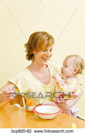 Mother feeding messy baby View Large Photo Image Stock Image - Mother feeding messy baby. Fotosearch