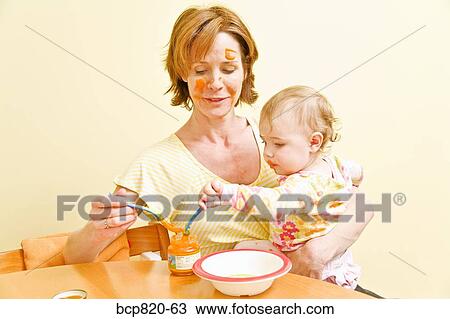 Mother feeding messy baby View Large Photo Image Stock Image - Mother feeding messy baby. Fotosearch