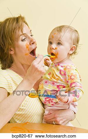 Mother feeding messy baby View Large Photo Image Stock Photo - Mother feeding messy baby. Fotosearch