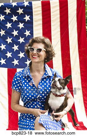 Stock Photo - Patriotic woman and Boston Terrier dog posing with American flag. Fotosearch
