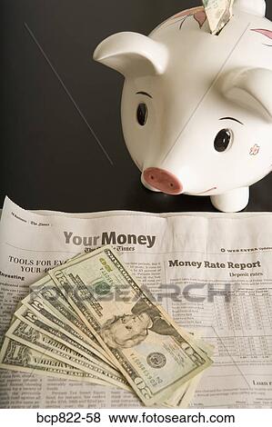 Stock Photo - Piggy bank, cash and financial section of newspaper. Fotosearch