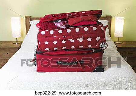 Two red suitcases stacked on a bed View Large Photo Image Stock Photo - Two red suitcases stacked on a bed. Fotosearch