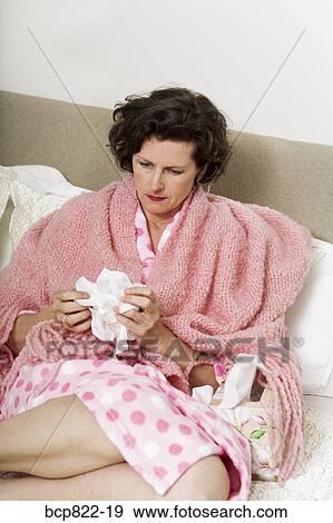 Unhappy woman holding tissue in bed View Large Photo Image Stock Photo - Unhappy woman holding tissue in bed. Fotosearch