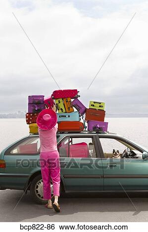 Woman adjusting stack of colorful suitcases on top of car View Large Photo Image Stock Photograph - Woman adjusting stack of colorful suitcases on top of car. Fotosearch
