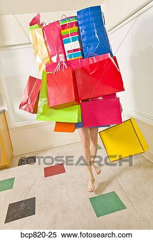 Stock Photography - Woman balancing assorted shopping bags. Fotosearch