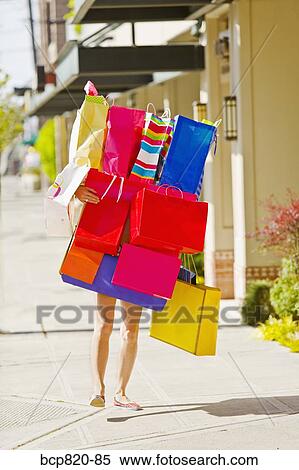 Stock Photography - Woman balancing assorted shopping bags. Fotosearch