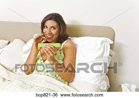 Woman eating chocolates in bed View Large Photo Image Stock Photograph - Woman eating chocolates in bed. Fotosearch