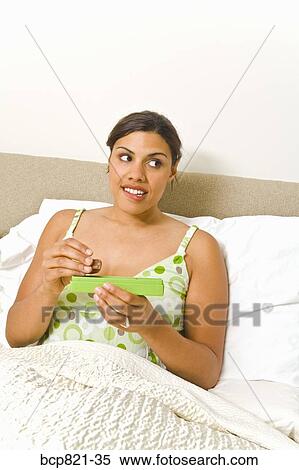 Stock Photography - Woman eating chocolates in bed. Fotosearch