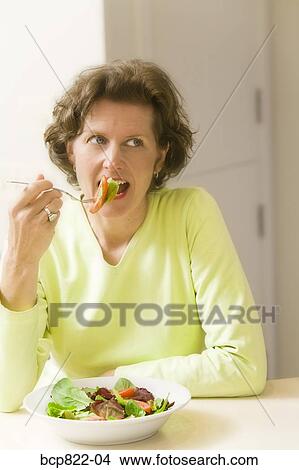 Picture - Woman eating healthy salad. Fotosearch