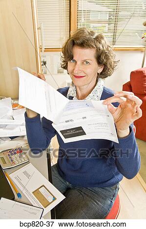 Woman holding bills in home office View Large Photo Image Stock Photo - Woman holding bills in home office. Fotosearch