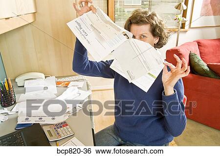 Woman holding bills in home office View Large Photo Image Stock Photograph - Woman holding bills in home office. Fotosearch