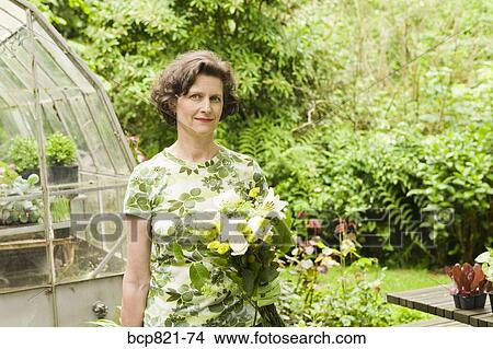 Woman holding flowers in garden View Large Photo Image Picture - Woman holding flowers in garden. Fotosearch