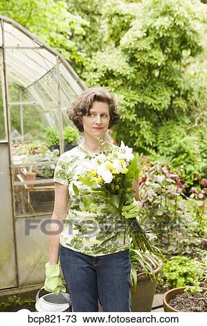 Woman holding flowers in garden View Large Photo Image Stock Image - Woman holding flowers in garden. Fotosearch