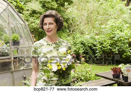 Woman holding flowers in garden View Large Photo Image Stock Photo - Woman holding flowers in garden. Fotosearch