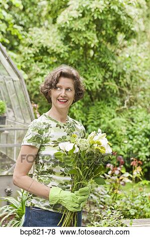 Woman holding flowers in garden View Large Photo Image Stock Photo - Woman holding flowers in garden. Fotosearch