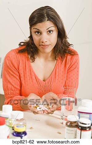 Stock Image - Woman holding handful of vitamins and supplements. Fotosearch