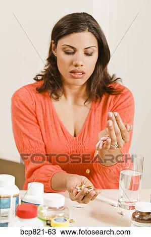 Stock Image - Woman holding handful of vitamins and supplements. Fotosearch